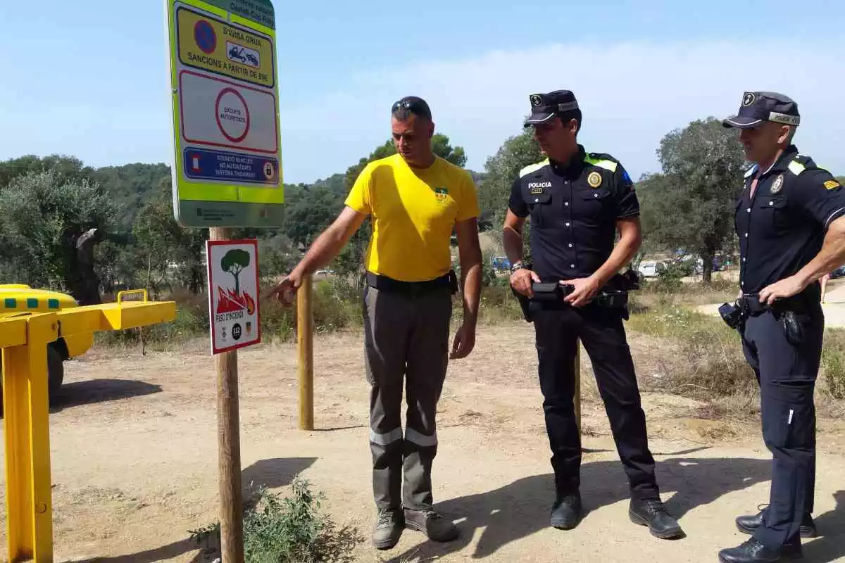 Pla mitjà de dos agents de la policia amb un operari a l'espai natural de Castell-Cap Roig, a Palamós