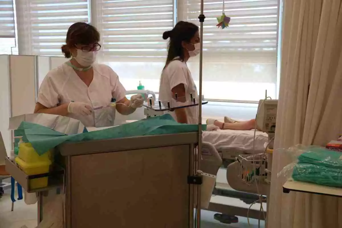 Dues infermeres atenent un nen fent tractament a l'Hospital de Dia de Vall d'Hebron (18/06/2018).