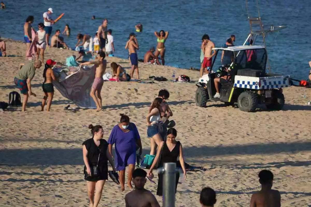 Imatge de la platja de la Nova Icària de Barcelona durant l'estiu de 2020, amb diversos banyistes i un vehicle de la Guàrdia Urbana
