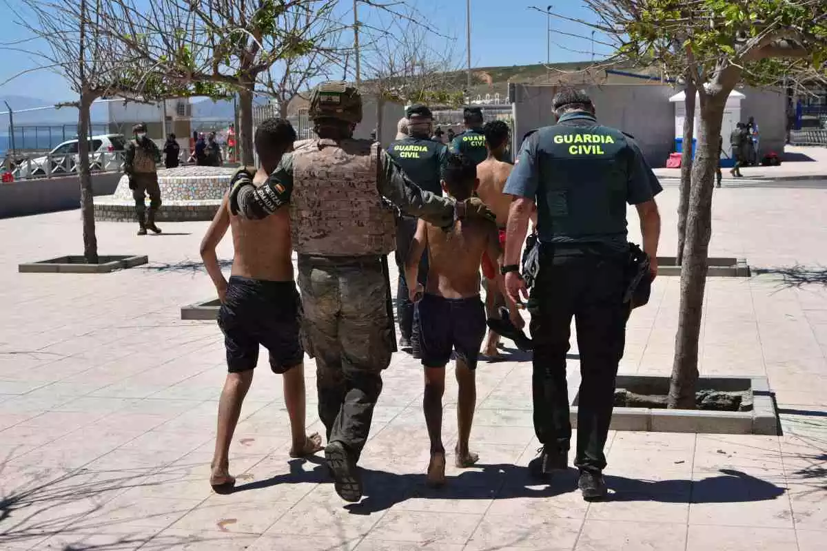Un soldat espanyol i un agent de la Guàrdia Civil ajuden a dos menors migrants procedents del Marroc a la seva arribada a Ceuta