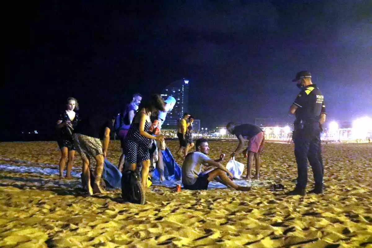 Un grup de persones que feia 'botellón' a la platja de la Barceloneta s'aixequen davant la presència d'agents de la Guàrdia Urbana