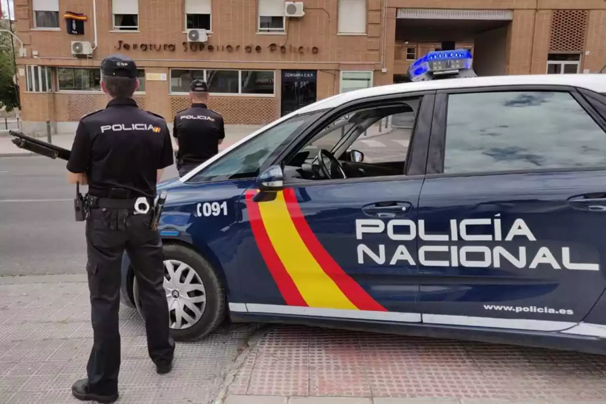 Dos agents i un cotxe de la Policia Nacional al carrer