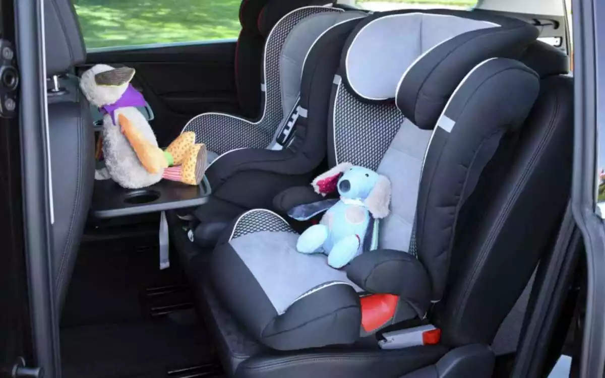 Dues cadiretes de nadons dins d'un cotxe amb peluixos