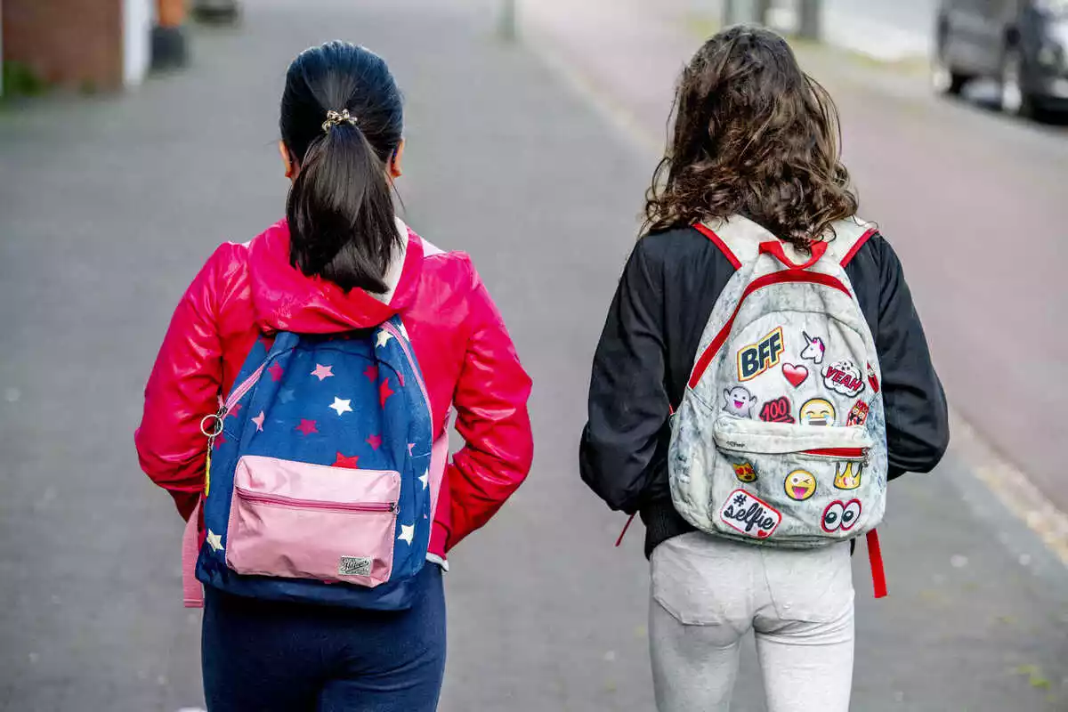 Dues nenes d'esquenes amb motxilles anant al col·legi