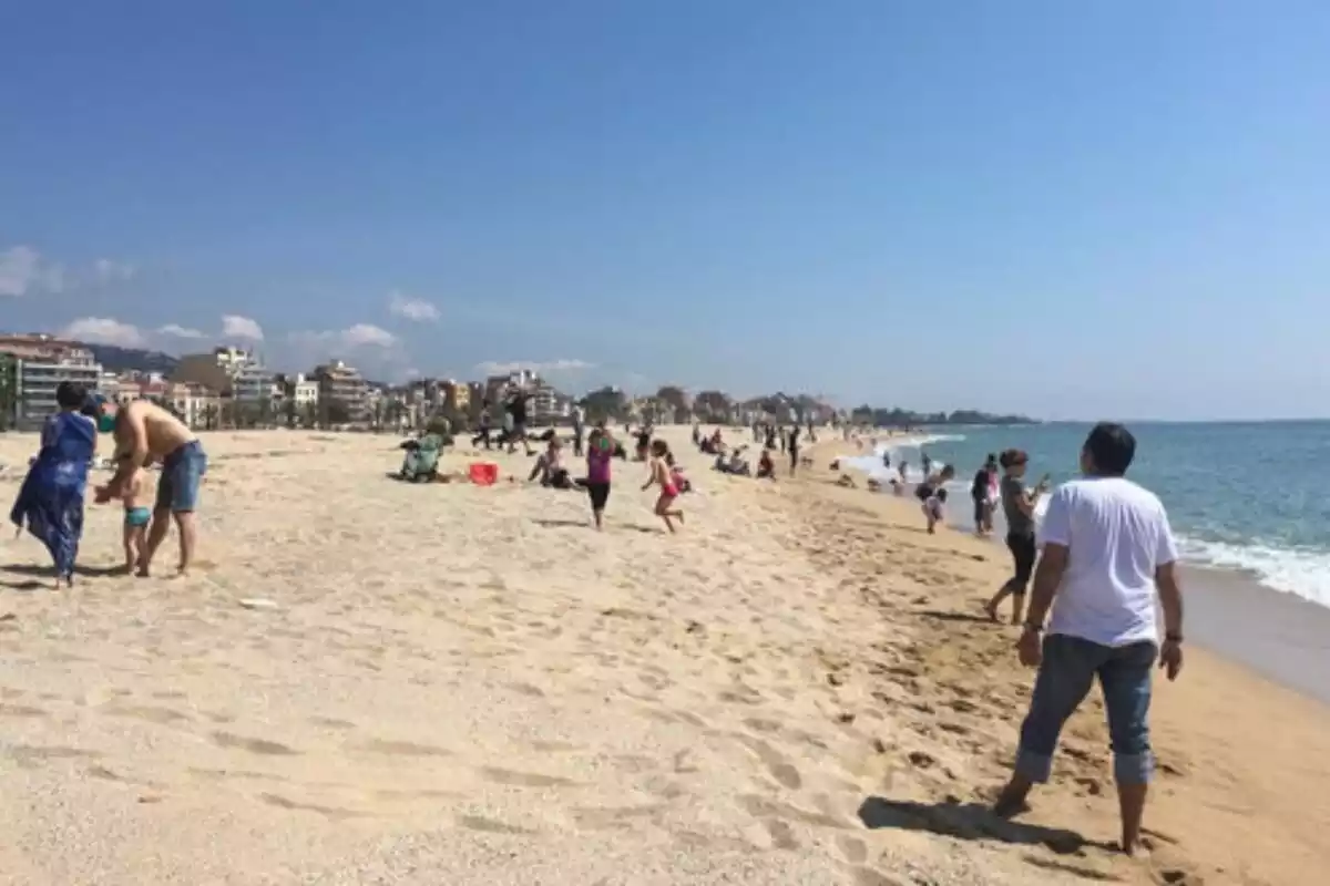 Imatge de la platja del Masnou amb gent banyant-se i caminant