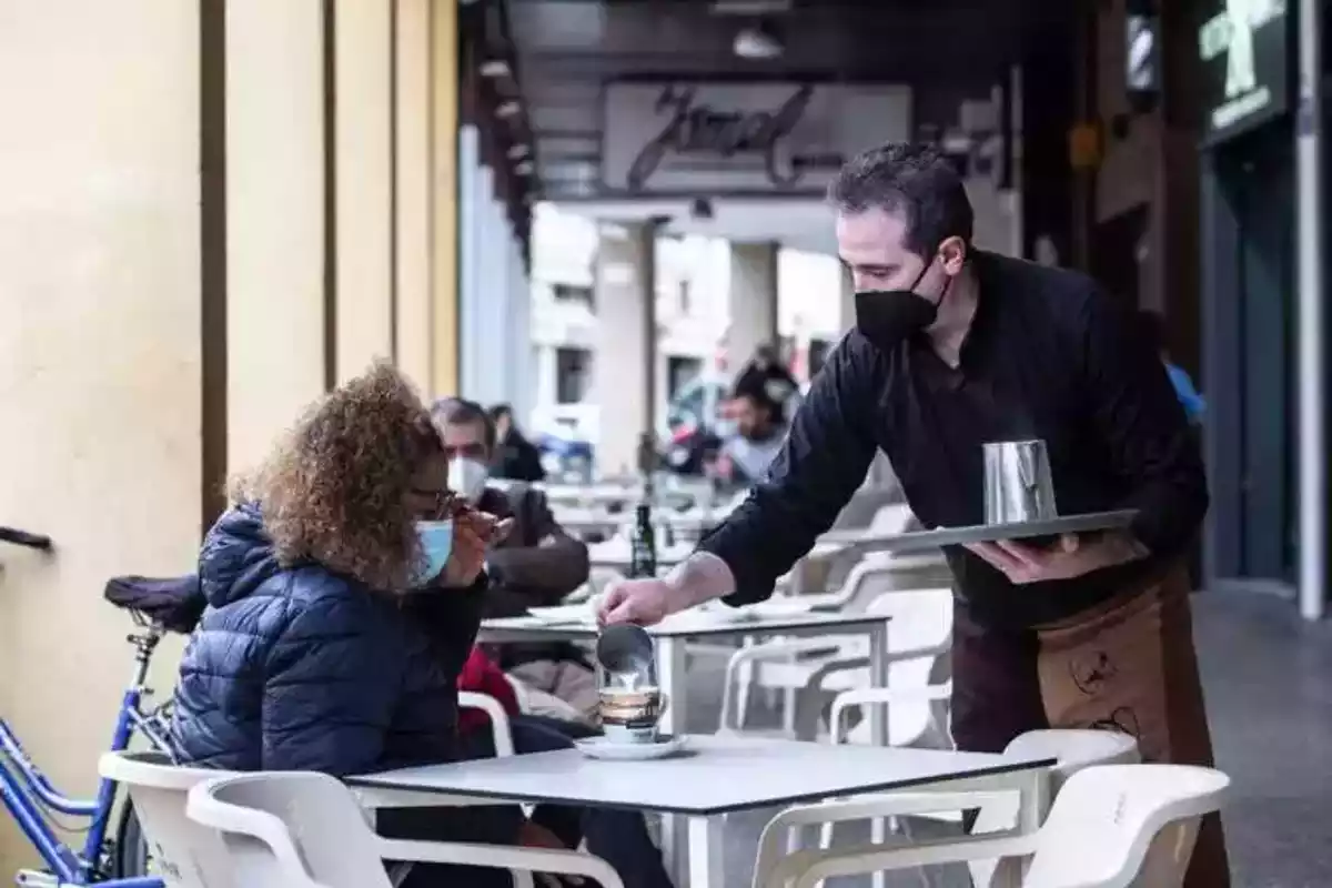 Imatge d'un cambrer servint un cafè a una clienta.