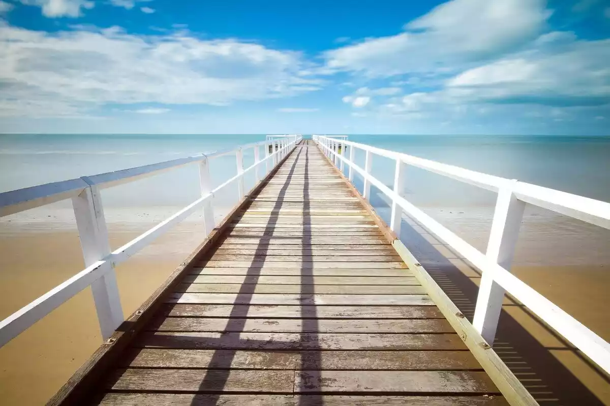 Imatge d'una platja amb una passarel·la de fusta