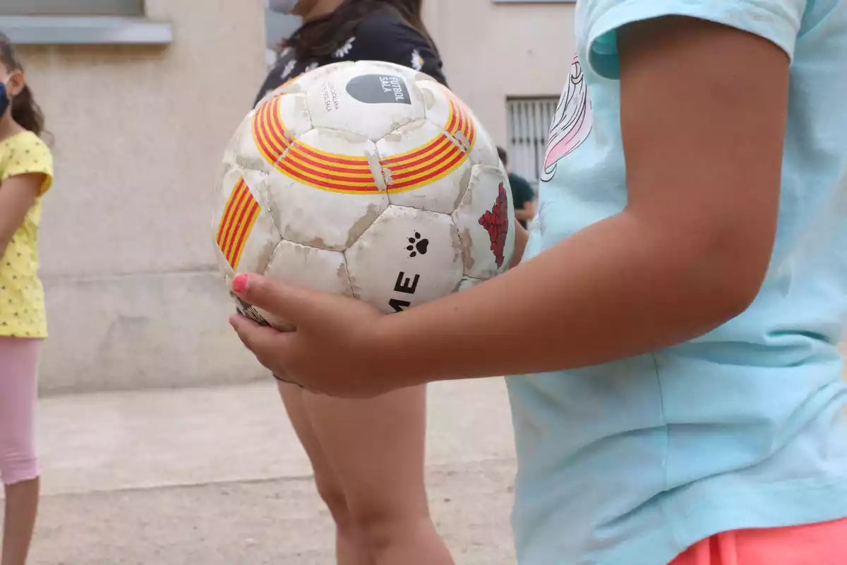 Pla detall d'una pilota a les mans d'una nena participant al casal d'estiu de la Fundació Pere Tarrés