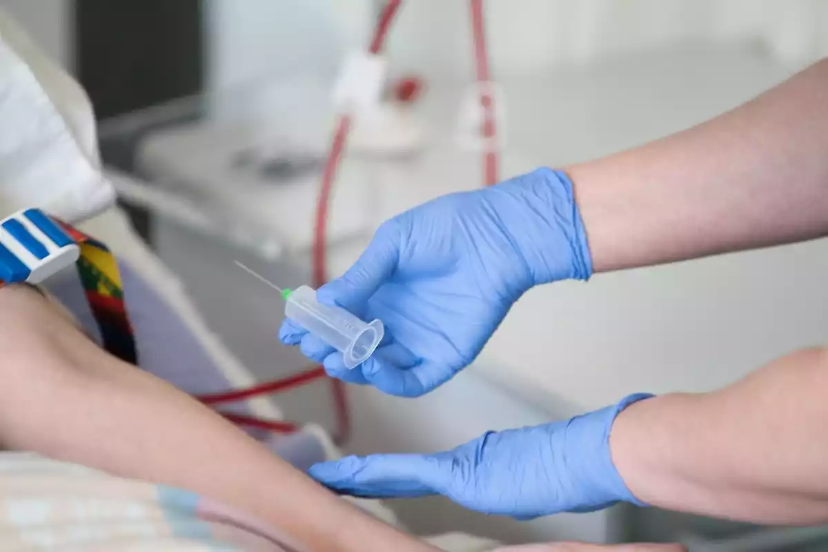 Primer pla de les mans d'un infermer administrant un medicament a un pacient