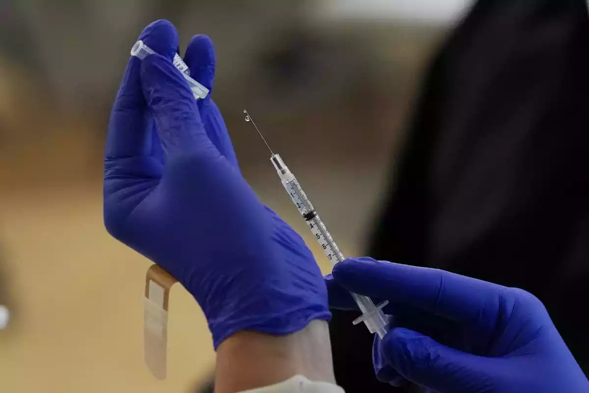 Primer pla de les mans d'un sanitari subjectant un vial de la vacuna de Pfizer