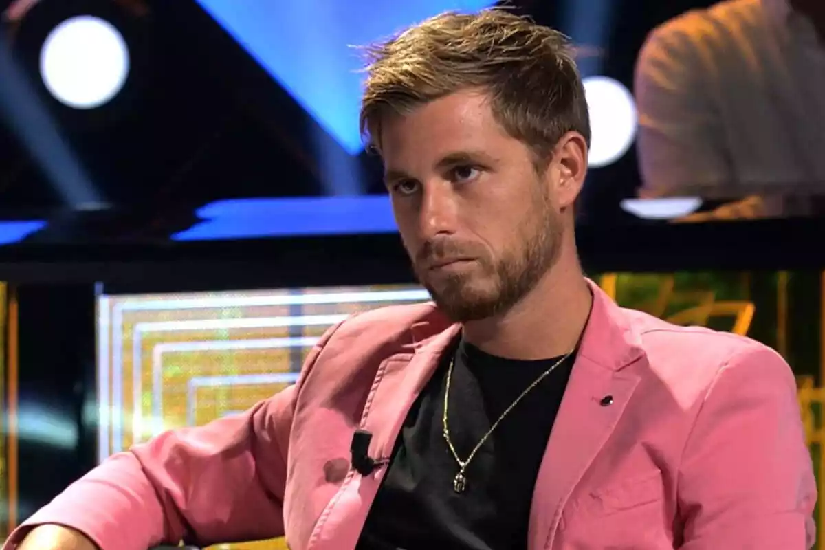 Tom Brusse amb rostre seriós i jaqueta rosa en un plató de Telecinco