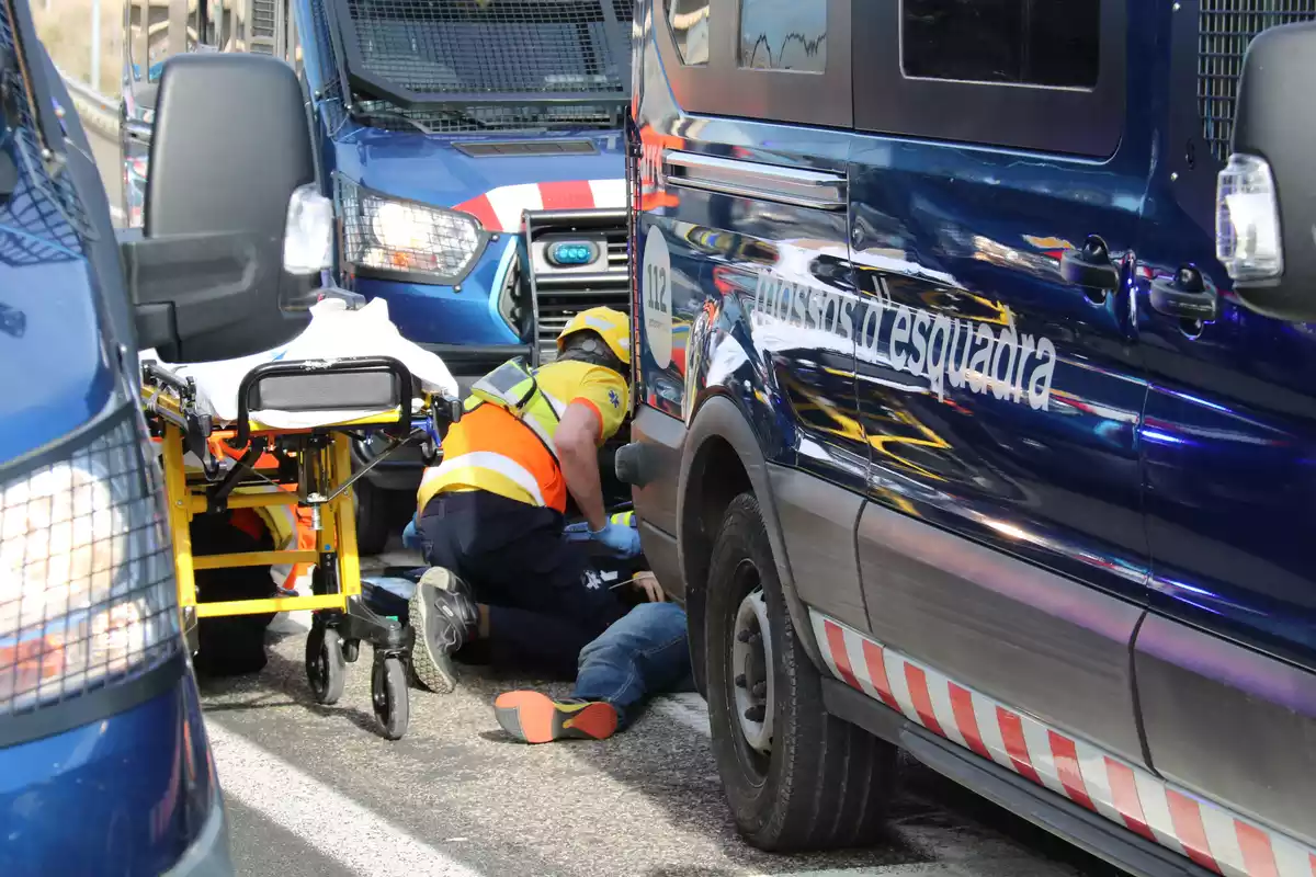 Un treballador del SEM atent una persona accidentada entre dues furgonetes dels Mossos d'Esquadra