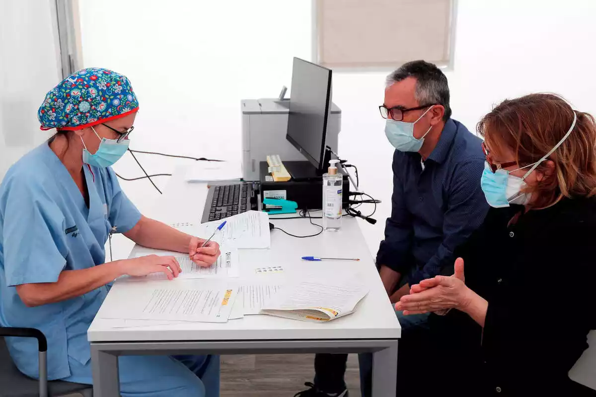 Una professional sanitària atenent dos pacients en una consulta mèdica