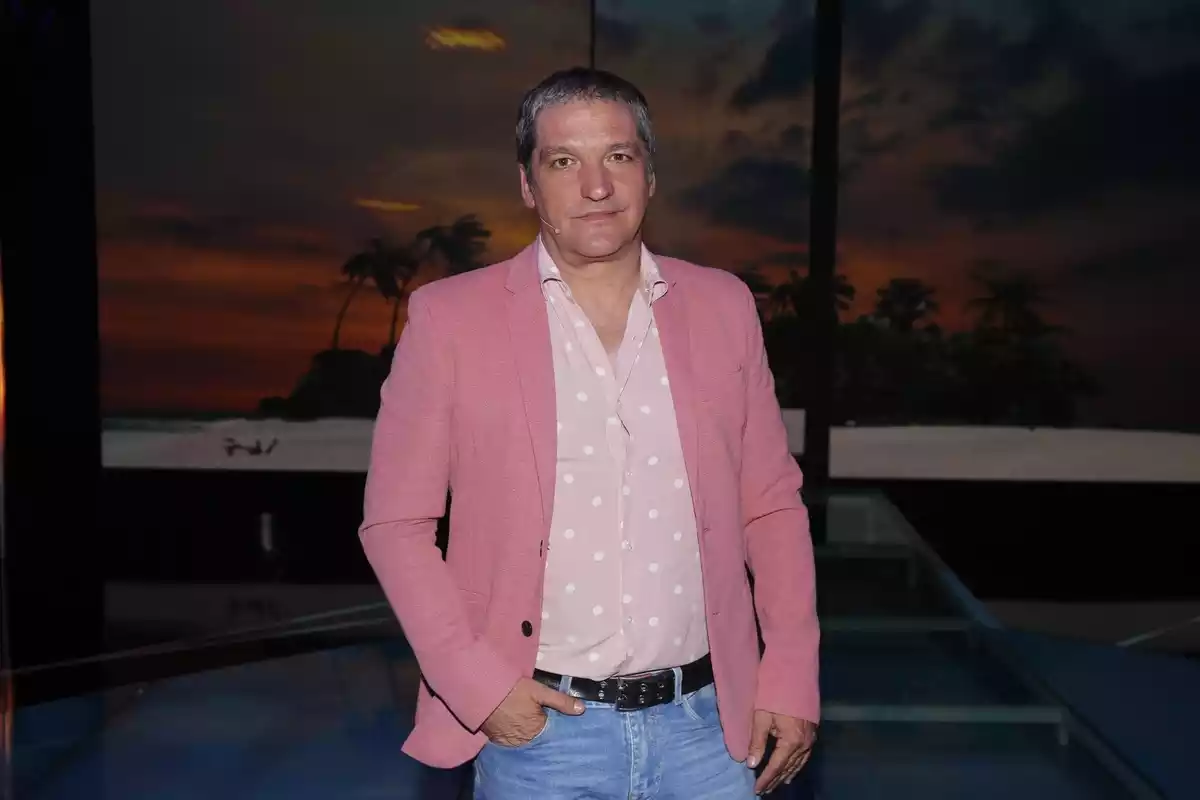 Gustavo González mirant a càmera somrient i vestint una americana rosa