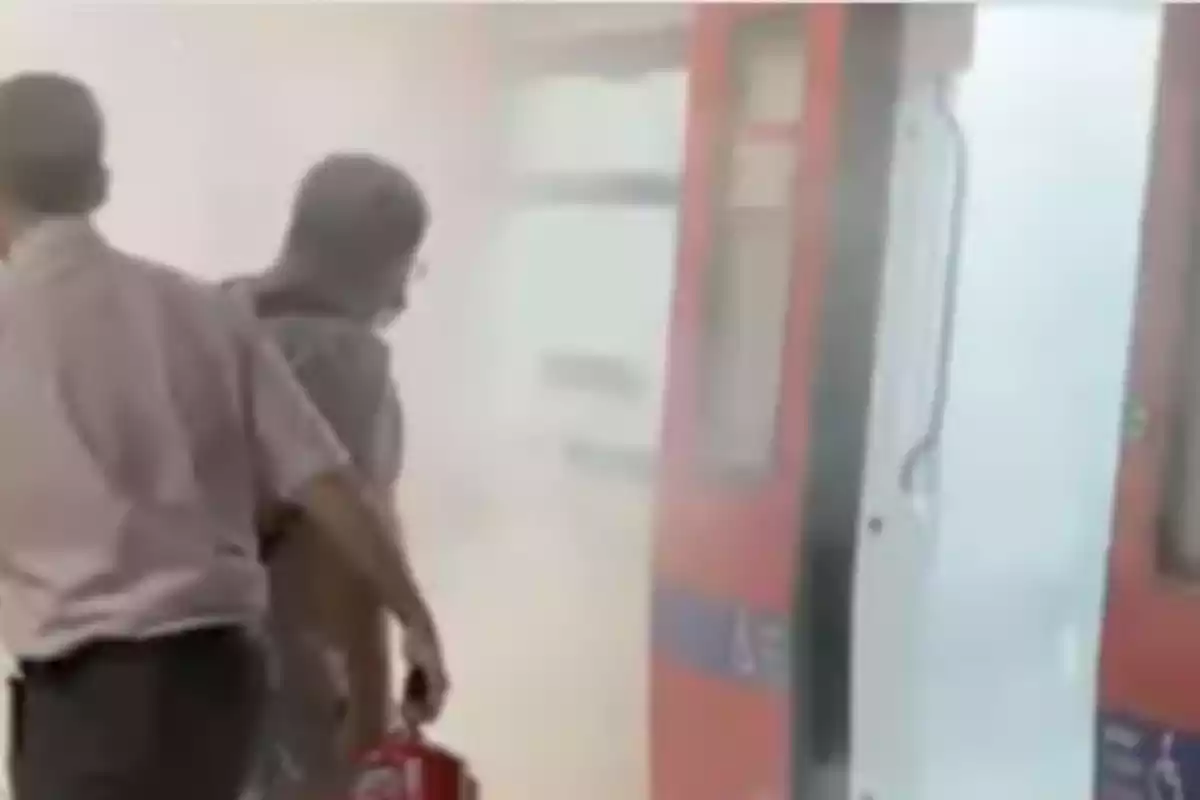 Imatge de dos operaris del metro de Barcelona intentant apagar les flames que s'han produït a l'estació de Diagonal