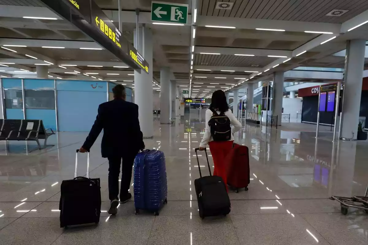 Imatges de dues persones amb maletes caminant per l'aeroport