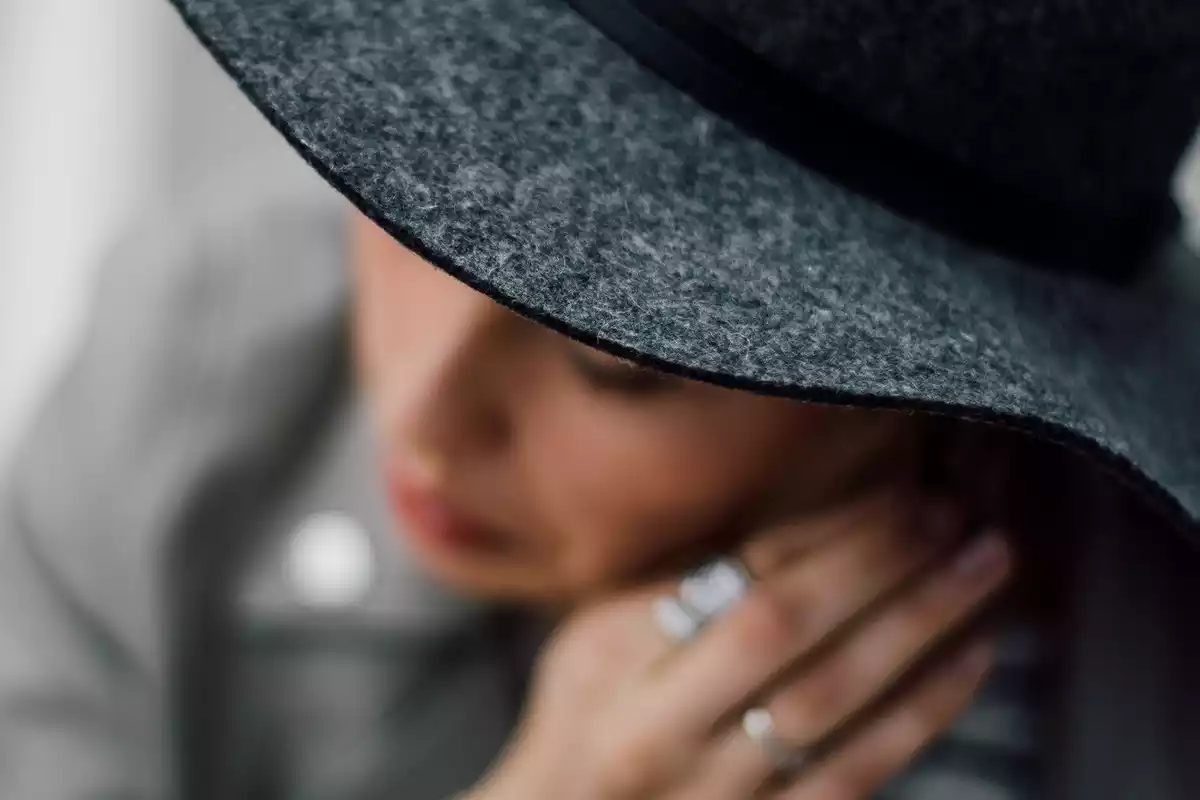 Pla difuminat d'una dona amb barret gris i uns anells a la mà