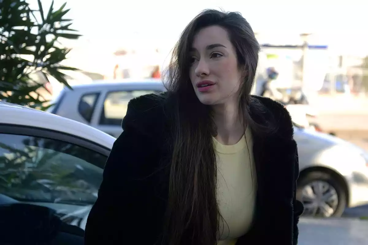 Adara Molinero enxampada al carrer amb el cabell llarg, abric negre i una samarreta groga