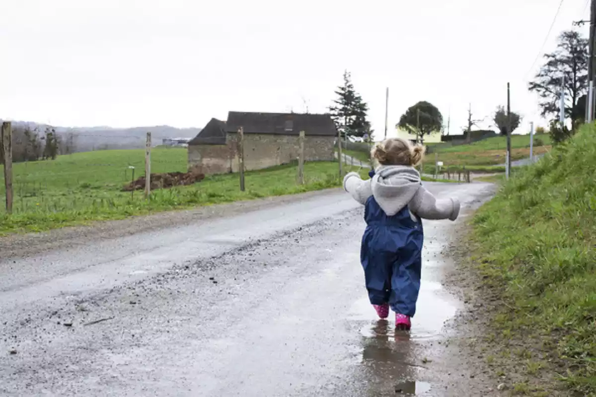 Imatge d'una nena petita caminant sola per un camí entollat