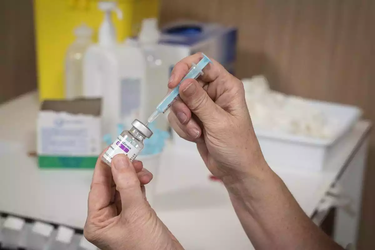 Un sanitari introduint una agulla a un pot de la vacuna d'AstraZeneca