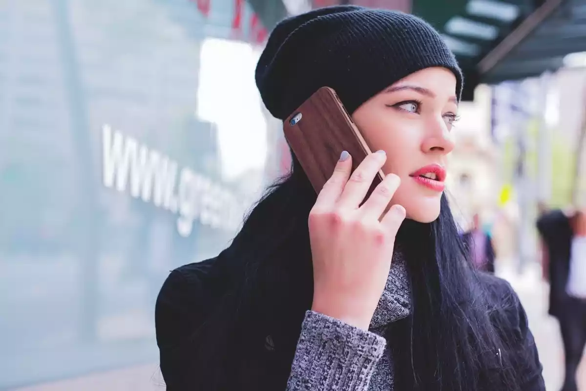 Una jove dona parlant per telèfon enmig del carrer