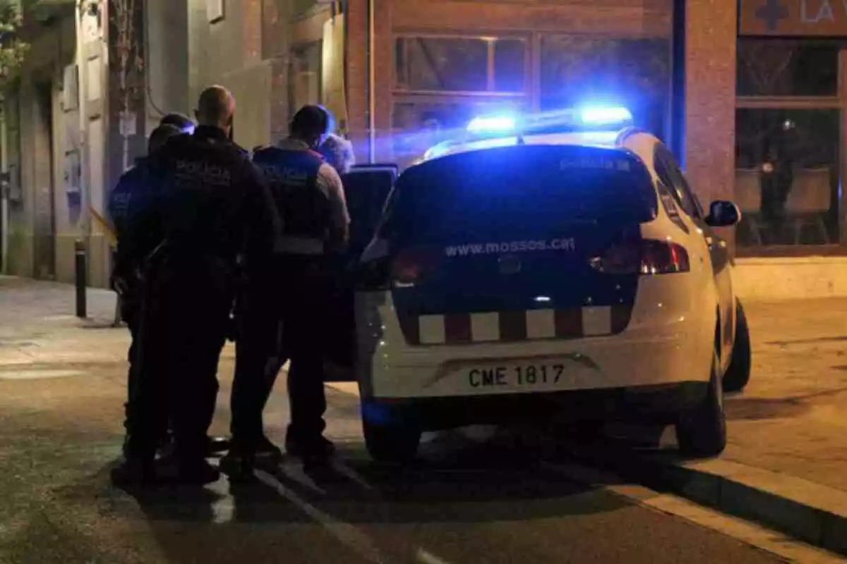 Els Mossos d'Esquadra, fent entrar al cotxe patrulla una persona detinguda durant la Festa Major de Sarrià