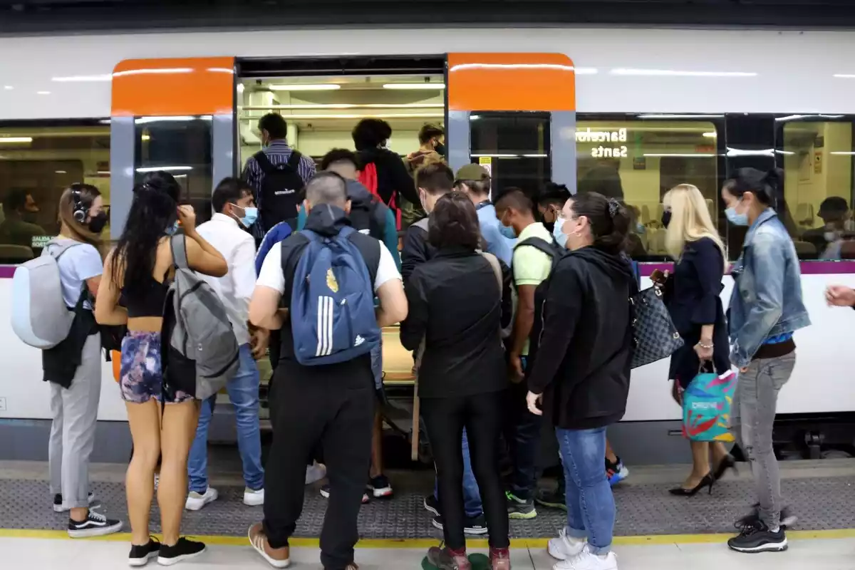 Un nombrós grup de gent intenta entrar a un tren a l'estació de Barcelona-Sants