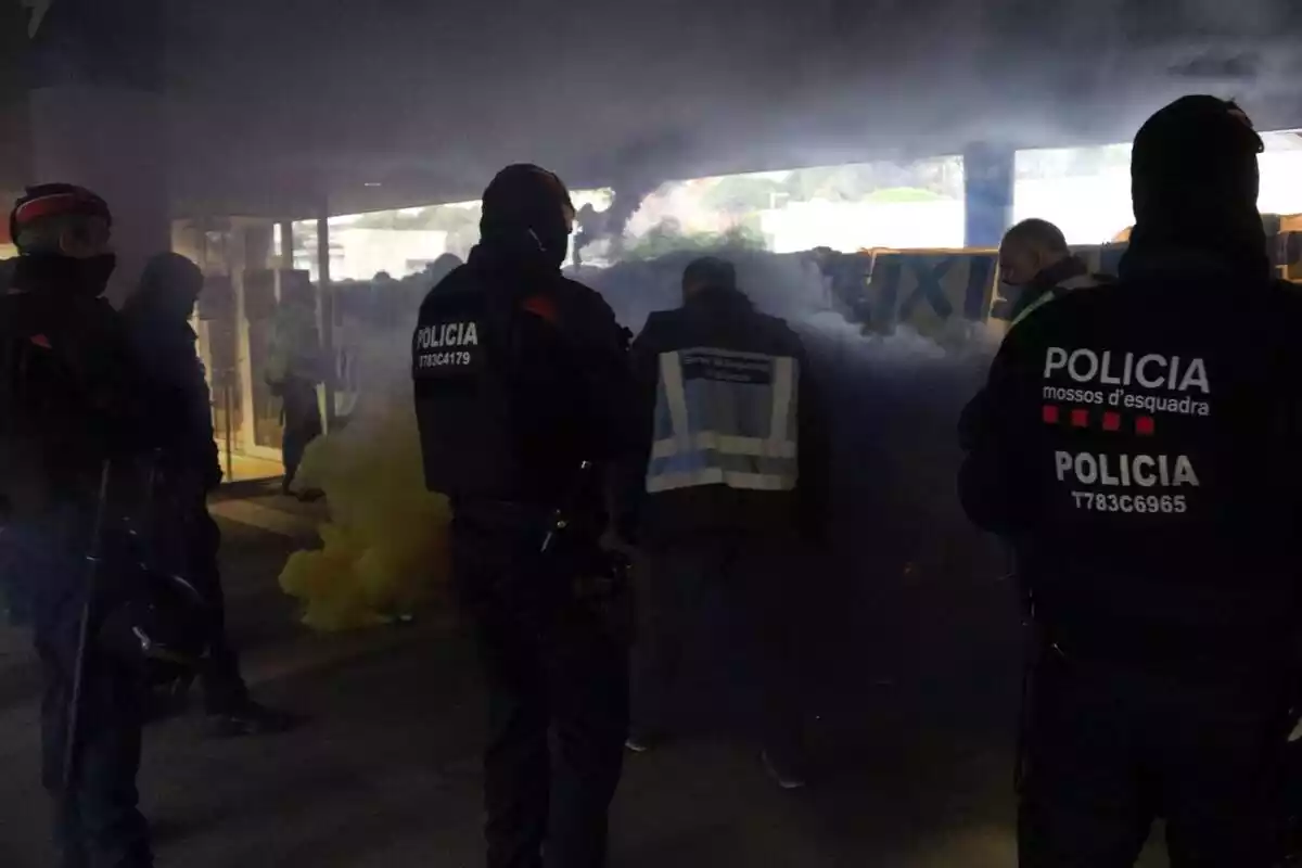 Agents dels Mossos d'Esquadra davant de la manifestació, amb algun pot de fum entremig