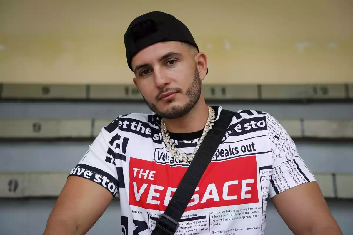 Omar Montes, un dels cantants més escoltats a Spotify a Espanya, mirant a càmera amb gorra i samarreta de Versace
