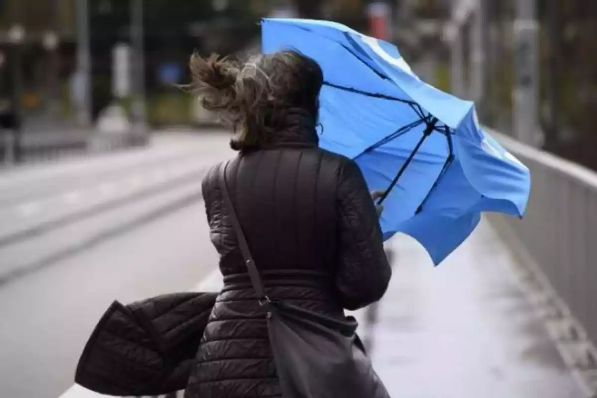 Imatge d'una dona amb el paraigües i molt vent.