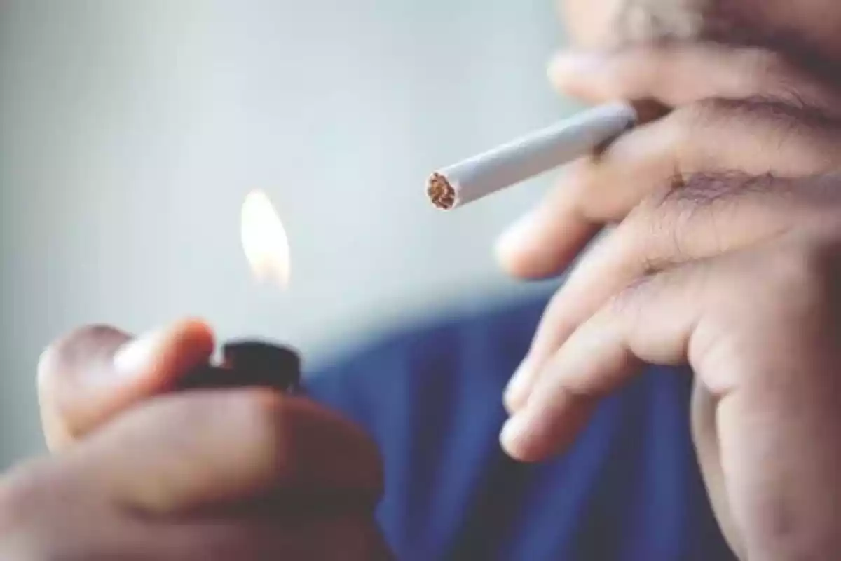Una persona encenent-se un cigarret