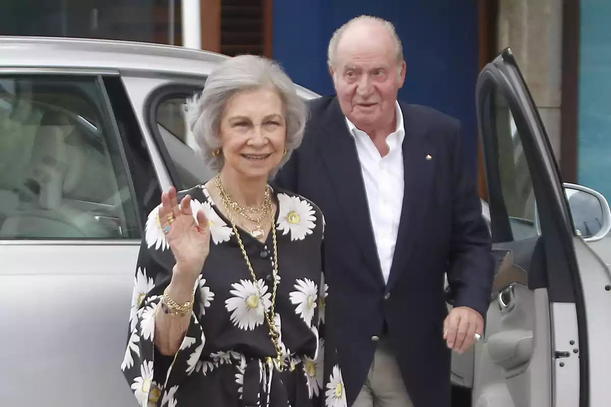 Imatge de la reina Sofia saludant a la premsa mentre que el rei Joan Carles surt del cotxe
