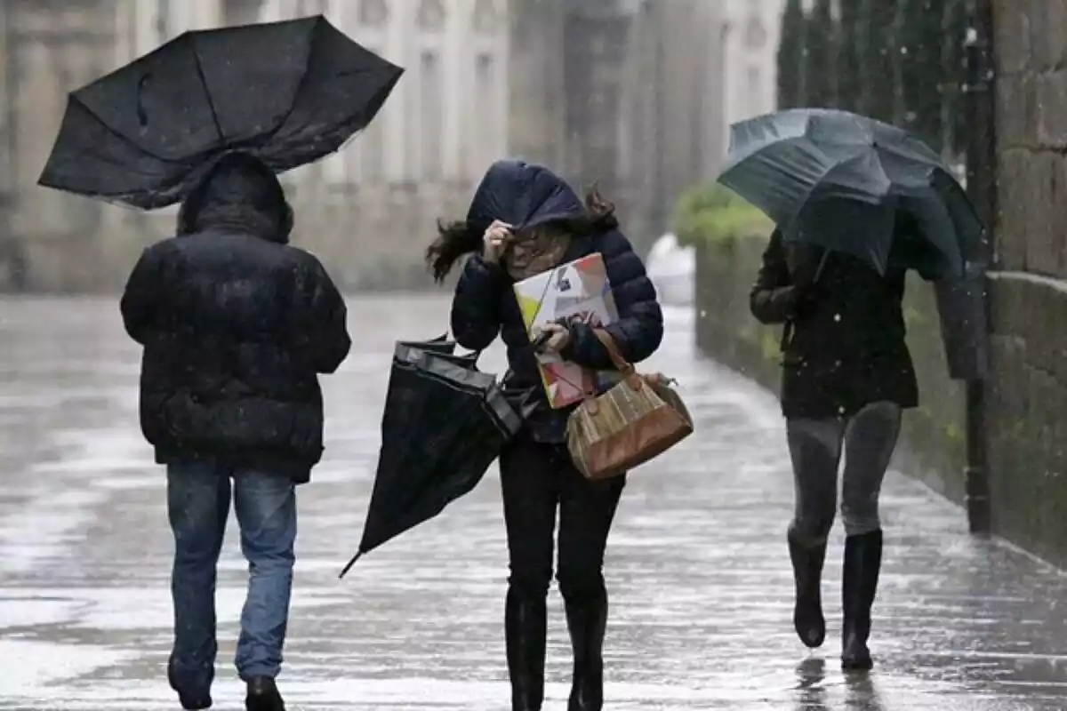 Imatge de persones caminant amb paraigües