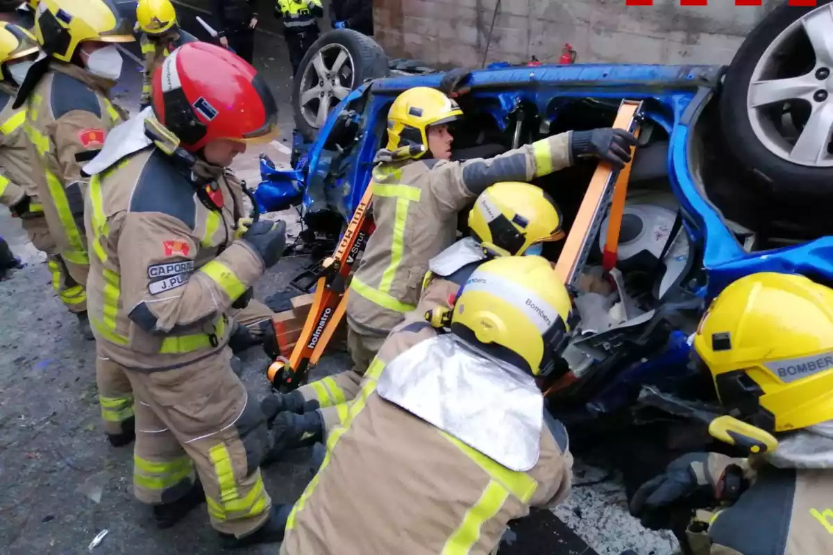 Els Bombers de la Generalitat treballant en el rescat de l'home ferit crític en estimbar-se amb el cotxe per un pont de l'N-II a Sant Pol de Mar