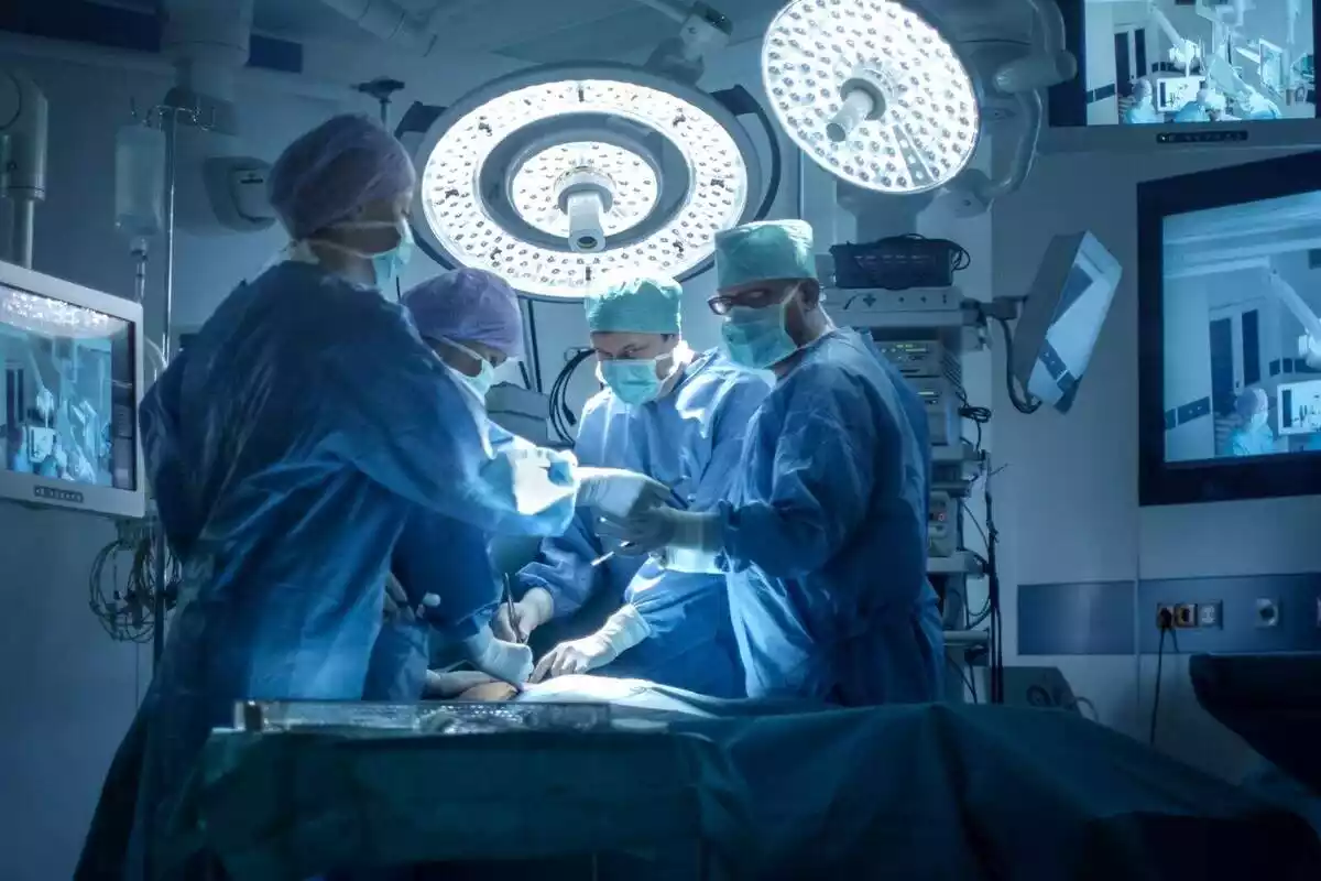 Imatge de quatre sanitaris realitzant una intervenció quirúrgica a un quiròfan