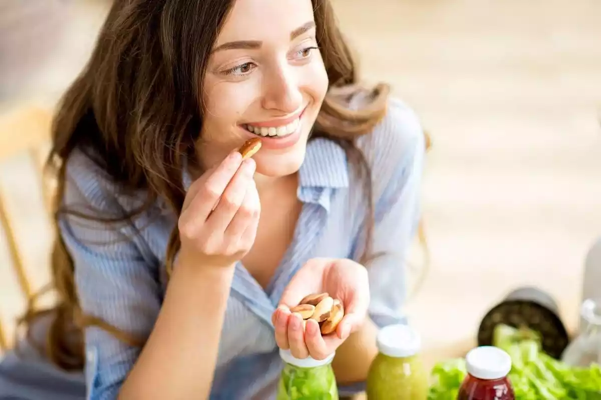 Imatge d'una noia menjant fruits secs mentre somriu