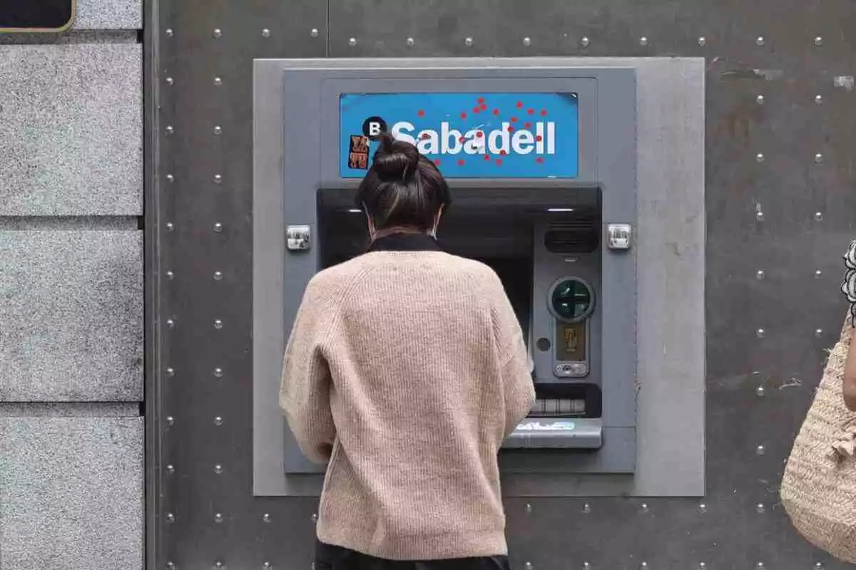 Imatge d'una dona treient diners al Banc Sabadell.