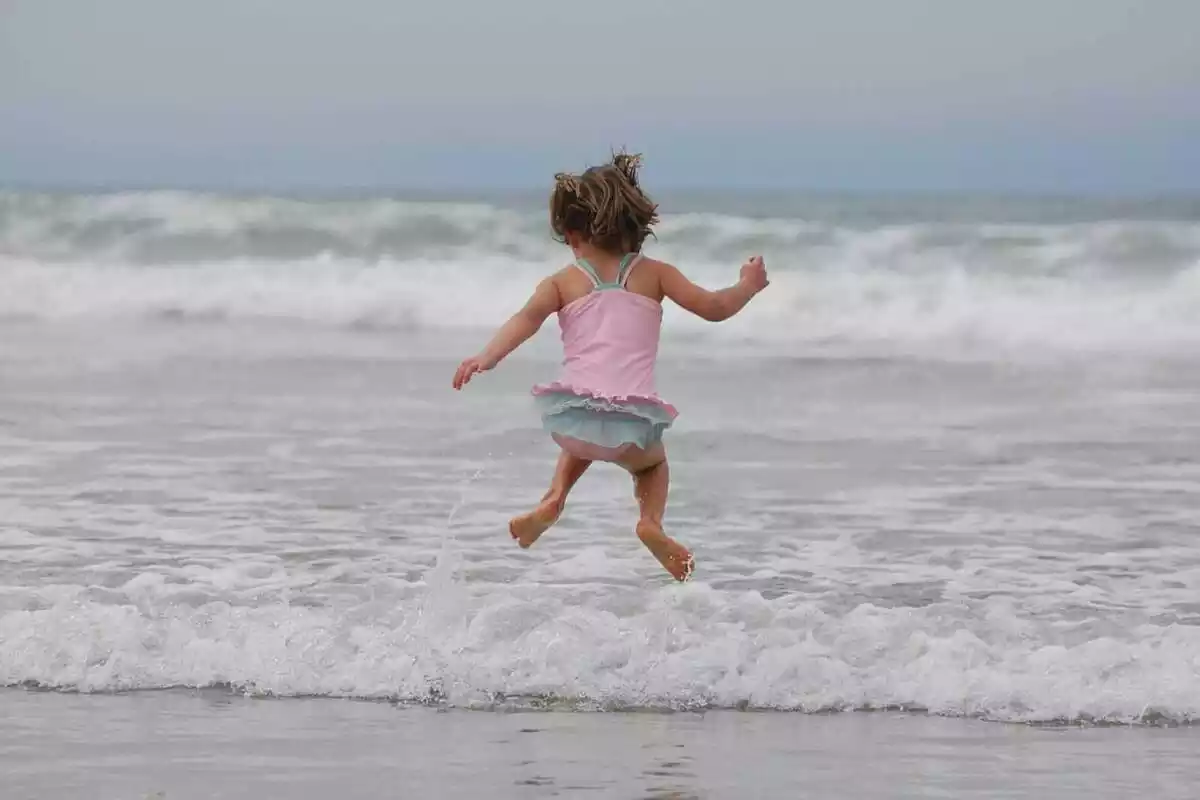 Imatge d'una nena saltant a la vora del mar