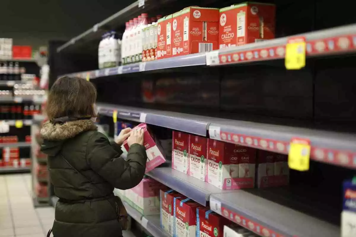 Imatge d'una senyora comprant llet en un supermercat.