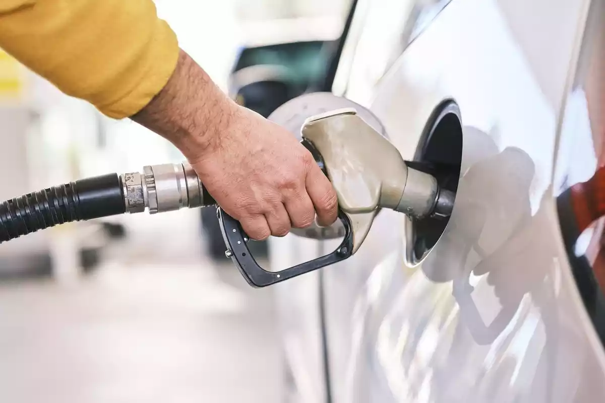 Primer pla del braç d'una persona posant gasolina a un cotxe