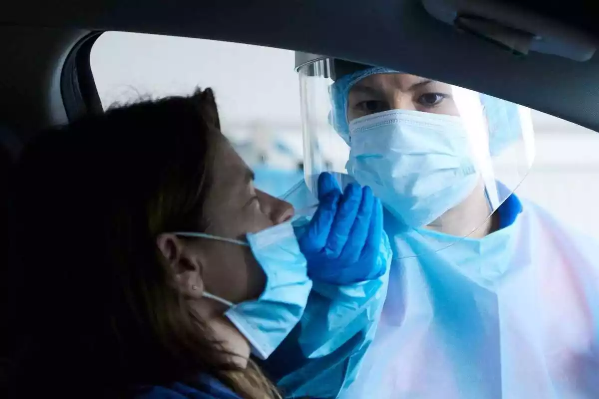 Sanitari fent una PCR dins d'un cotxe