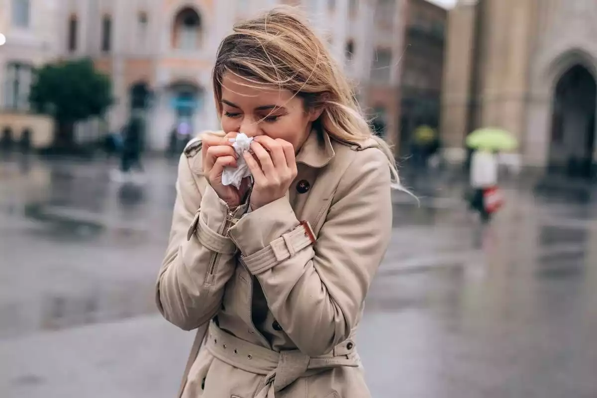 Una dona que esternuda pel carrer.
