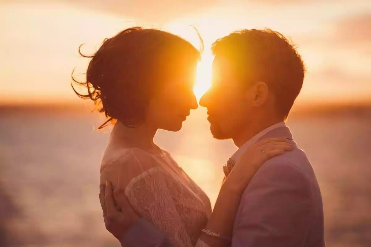 Una parella feliç amb la posta de sol al darrere.