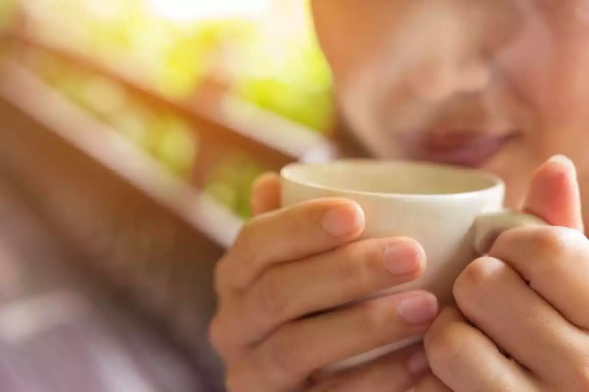 Una persona beu un te calent en una tassa.