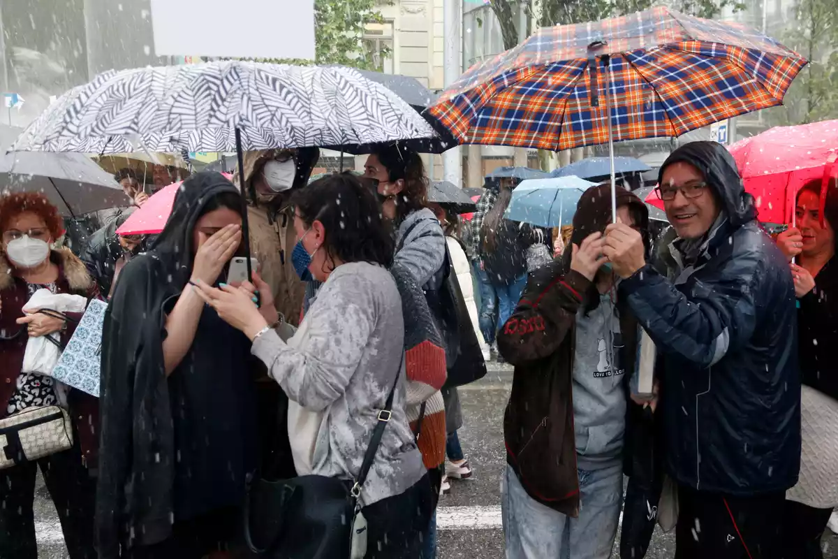 Diverses persones sota la pedregada davant les parades de llibres de Barcelona