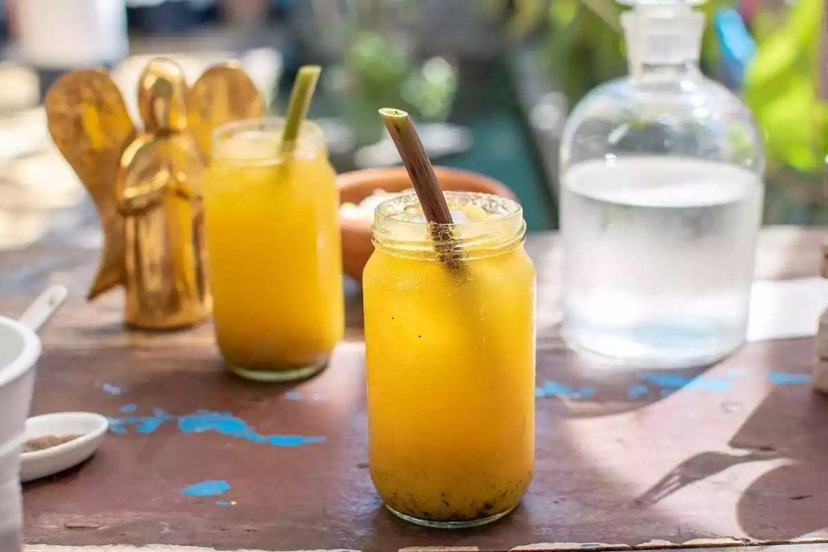 Imatge de dos gots amb una beguda de color groc i una jerra d'aigua al costat