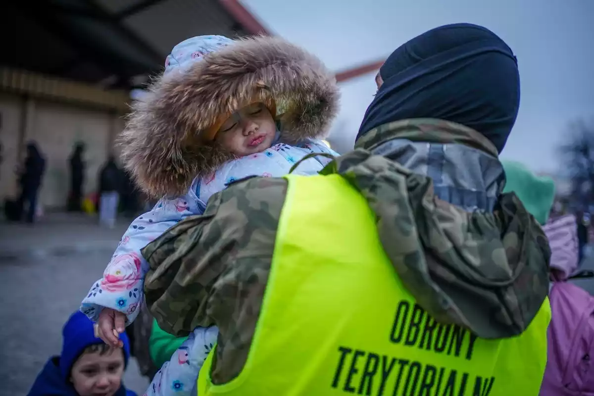 Imatge d'una nena petita ucraïnesa en braços d'un agent de les autoritats