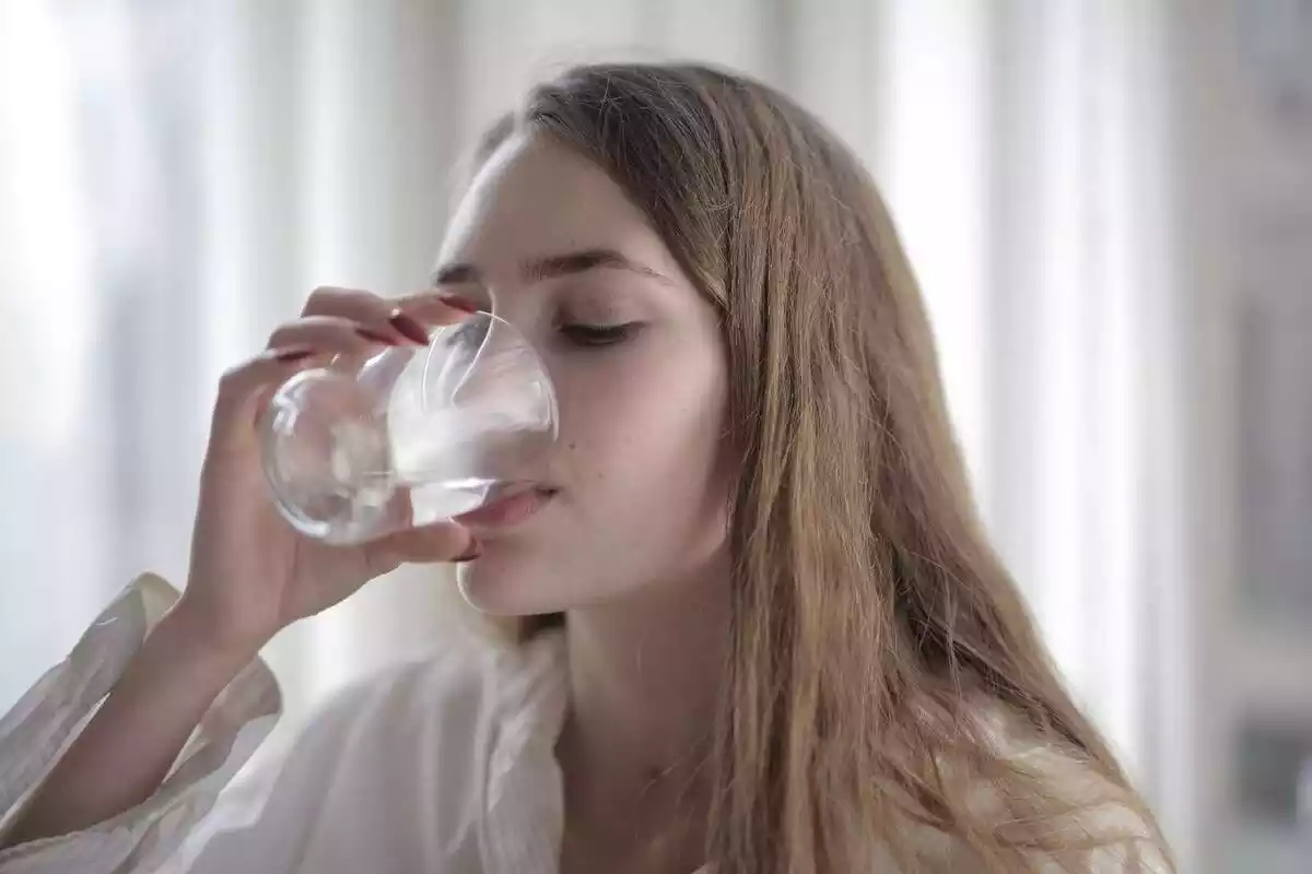 Noia bebent un got d'aigua