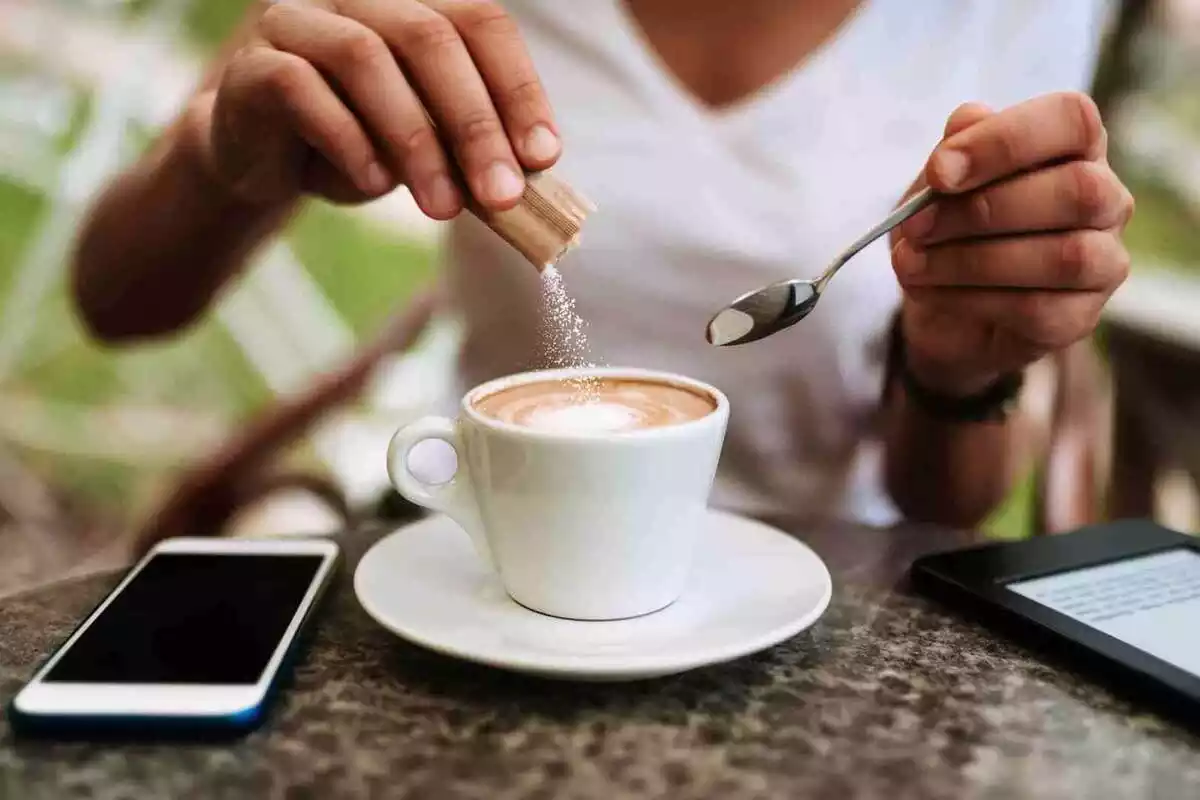 Detall d'una dona posant-se sucre al cafè