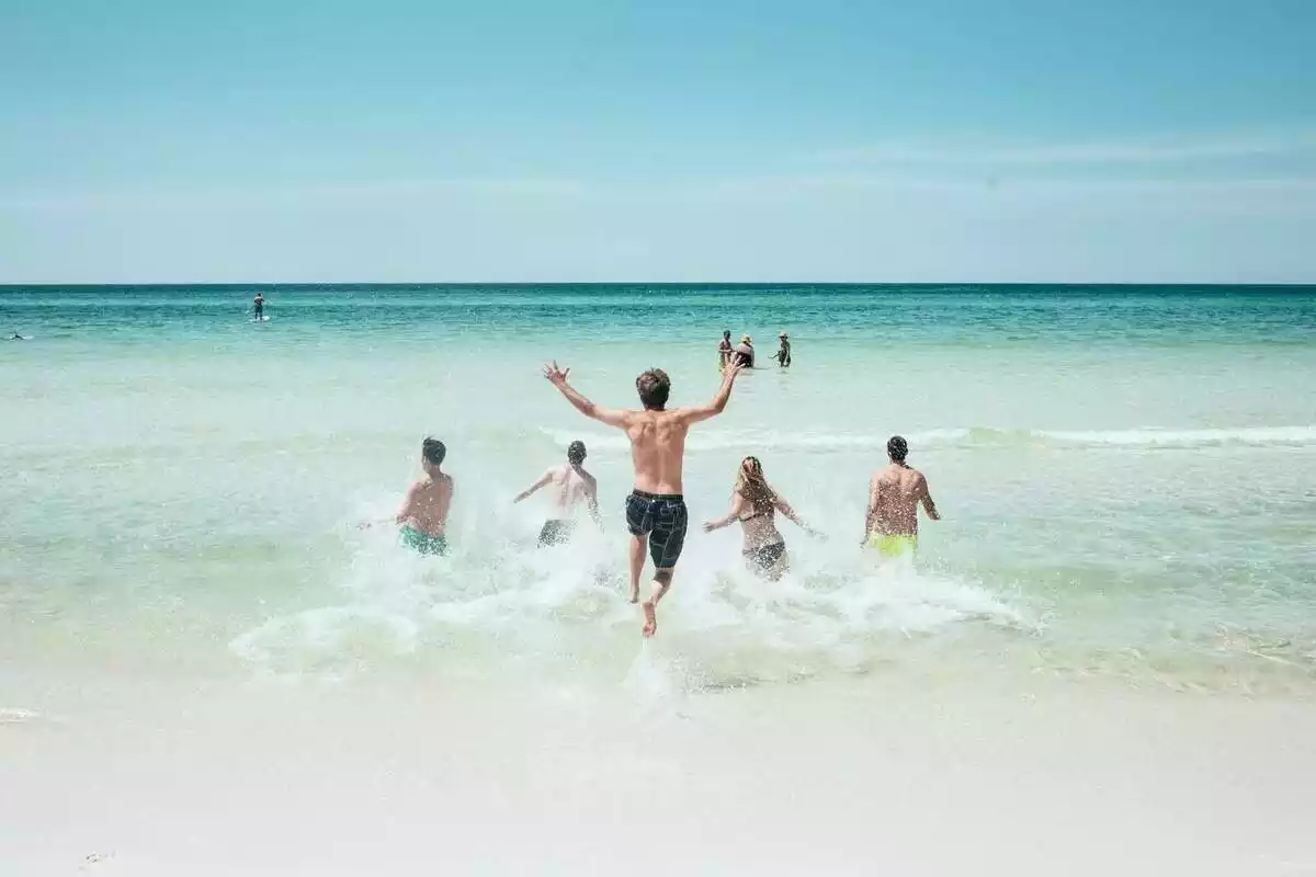 Imatge de diverses persones banyant-se a la platja
